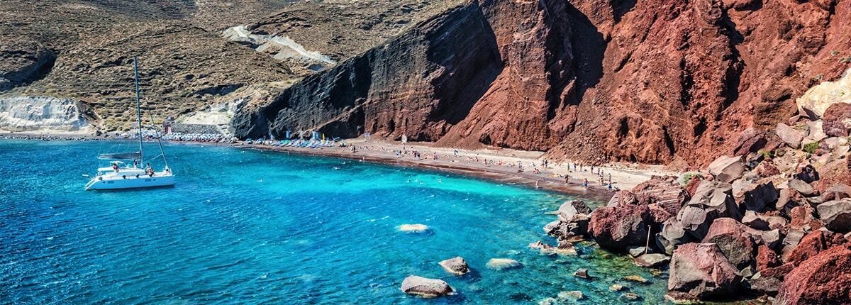 moutainous red beach with clear, teal water in santorini, greece