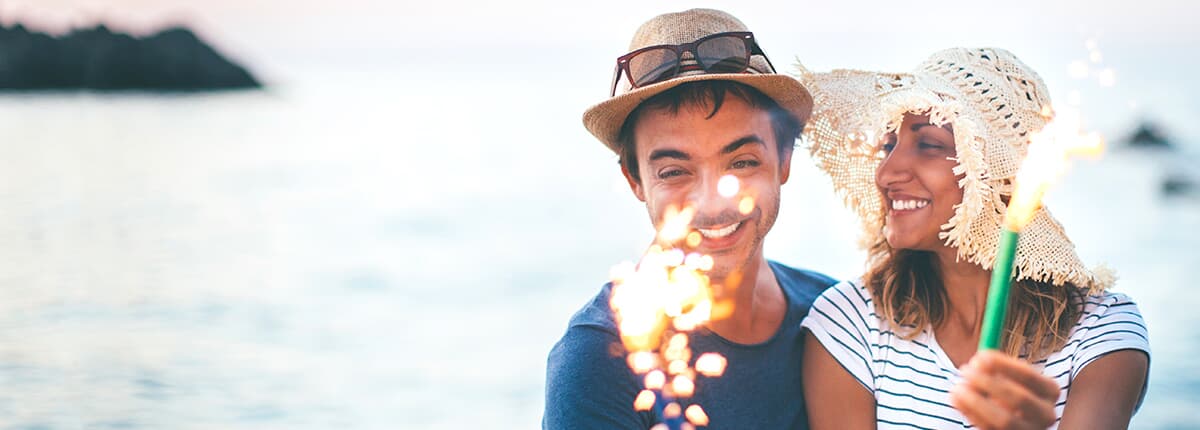 a man and woman playing with sparklers on a beach