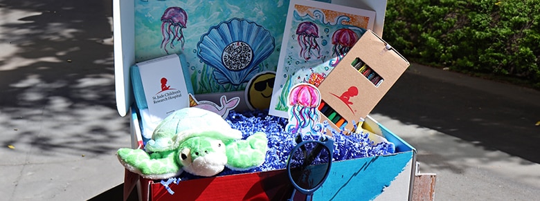 stuffed animal, sunglasses and coloring books with crayons inside a birthday box