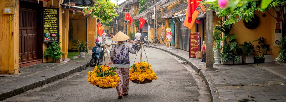 flower vendor walking through a traditional street in chan may vietnam