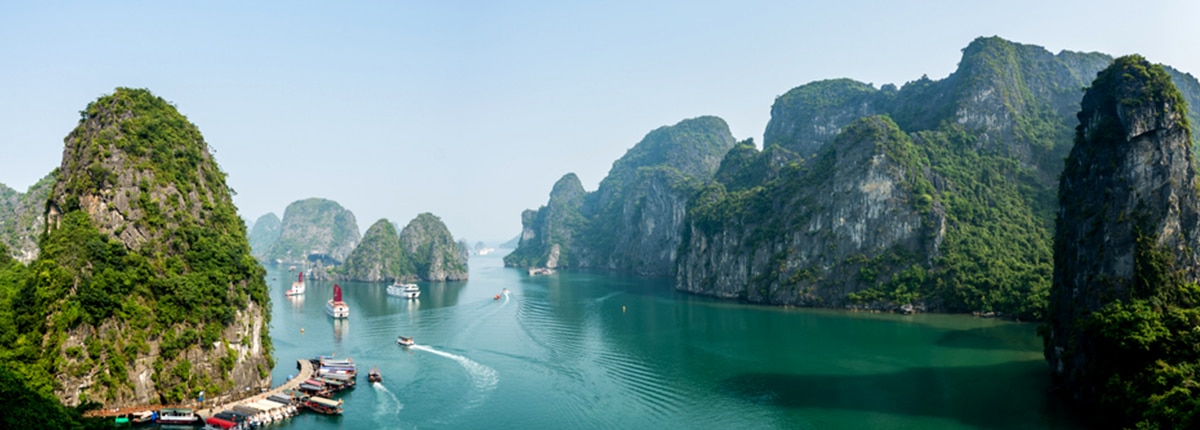 boats cruising through ha long bay Vietnam surrounded by limestone islands and emerald waters
