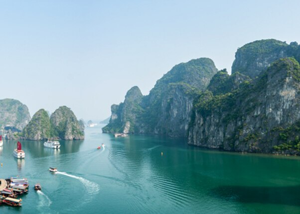 boats cruising through ha long bay Vietnam surrounded by limestone islands and emerald waters