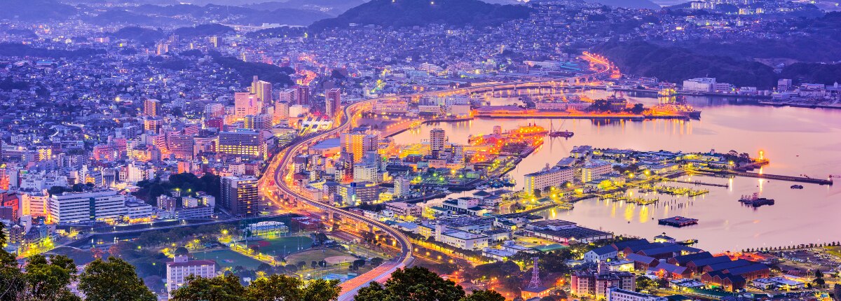 Aerial view of Sasebo, Japan, illuminated at dusk along the waterfront.