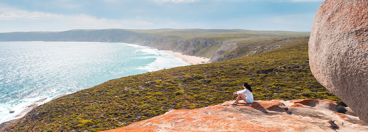 a woman sits on a large rock located in kangaroo island