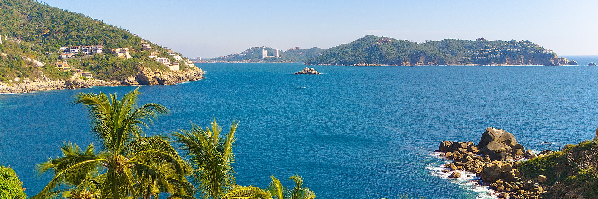 bay of rocky coast in acapulco with palm trees