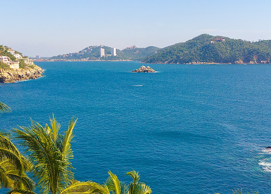 bay of rocky coast in acapulco with palm trees