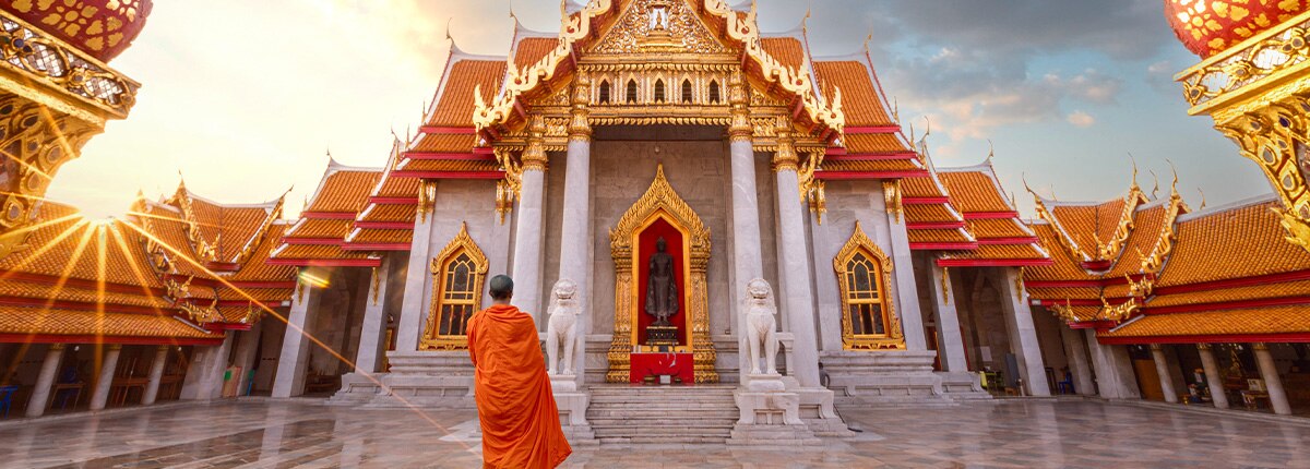 a monk stands infront of a temple located in laem chabang bangkok