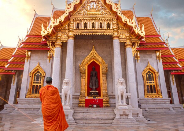 a monk stands infront of a temple located in laem chabang bangkok