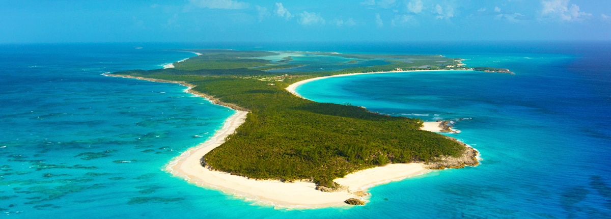 aerial of half moon cay with green trees and sandy, turquoise beaches