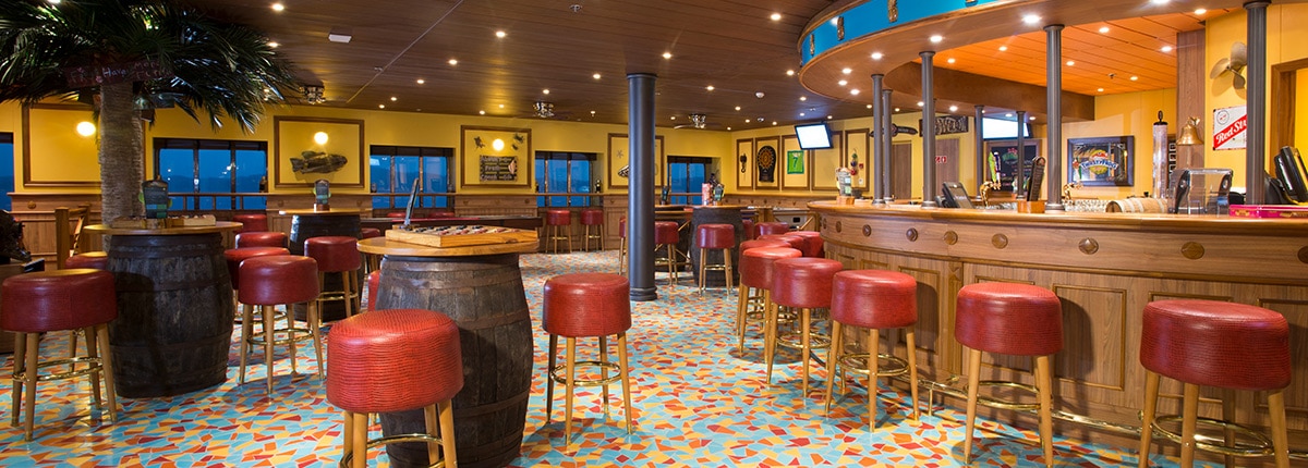red bar stools around a wood bar and barrel-shaped tables in the colorful redfrog pub