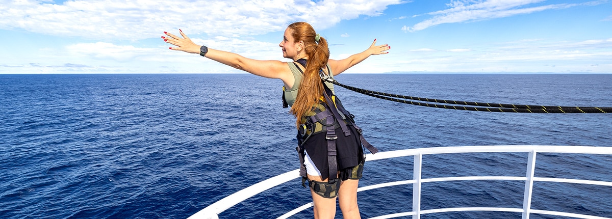 guest standing on a railing wearing a safety harness