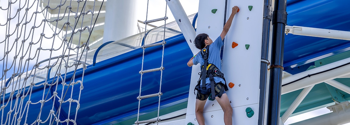 guest climbing up a rock wall onboard a carnival cruise