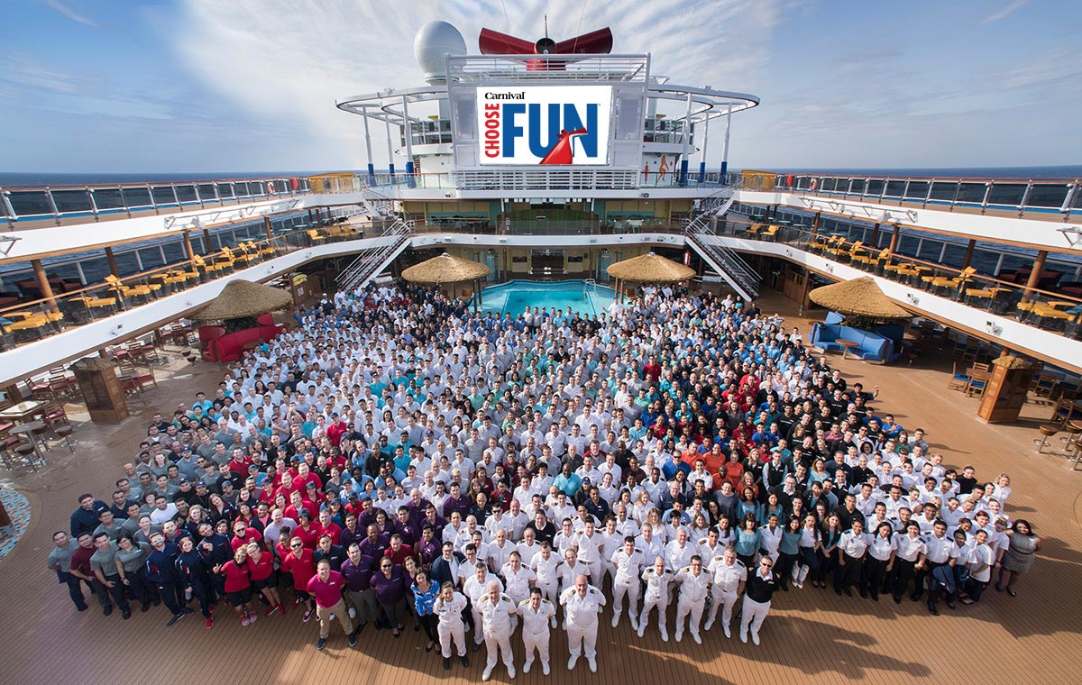 carnival cruise line staff stands together as one onboard a carnival cruise ship