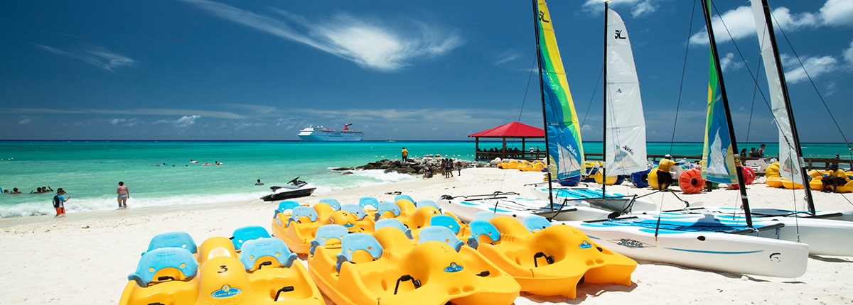 paddleboats and wind surfing kayaks lined on a beach in princess cays