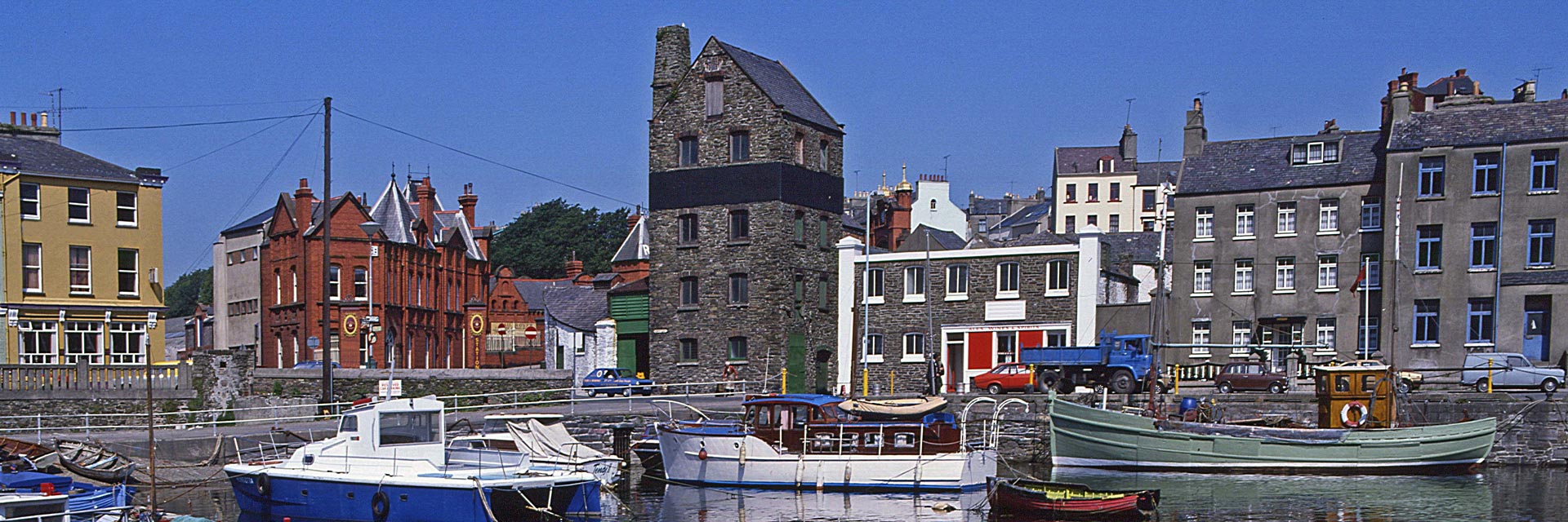 small boats are docked at a pier with brown stone buildings