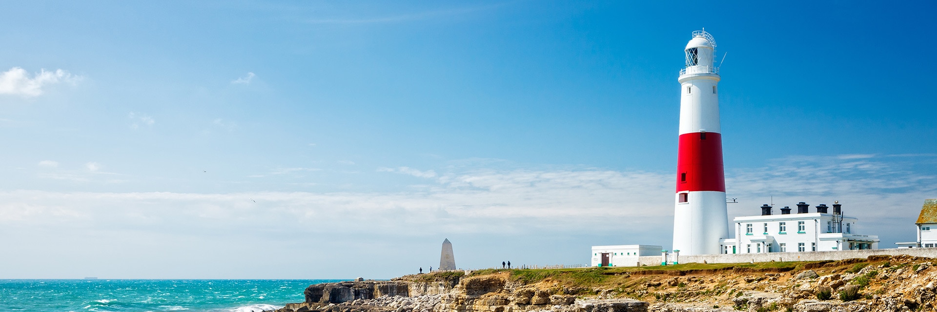 a red and white lighthouse is located on the edge of a cliff