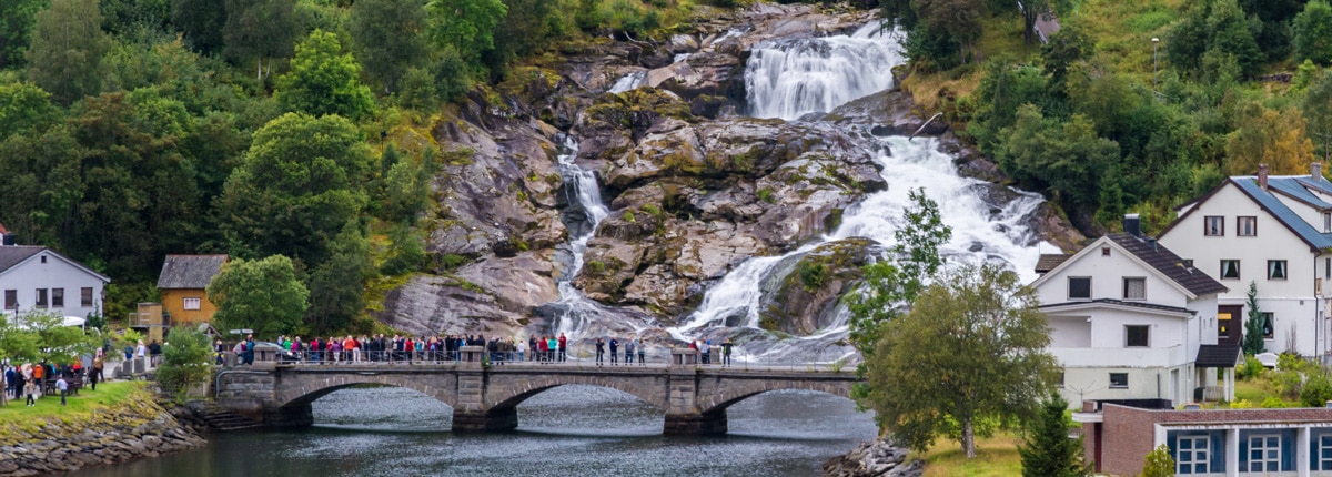 group of people gather on a bridge to watch a waterfall