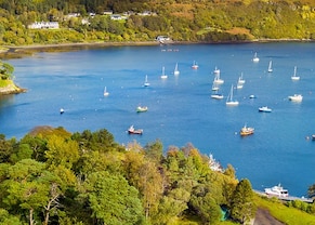 view of the green mountains and blue waters of portree, isle of skye, scotland