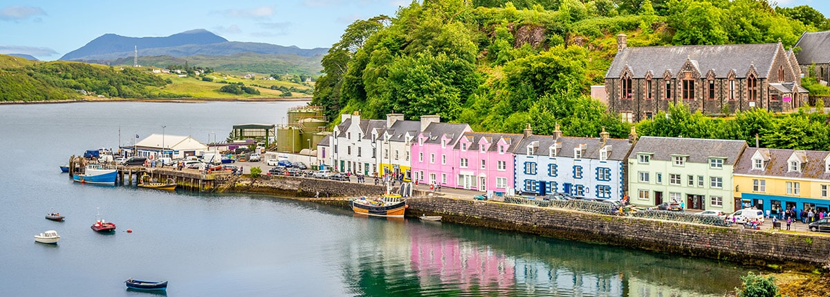 colorful houses and boats along a pier in portree, isle of skye, scotland