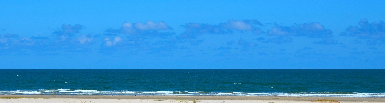 Beautiful blue skies and tranquil beach along the coast of Galveston, TX