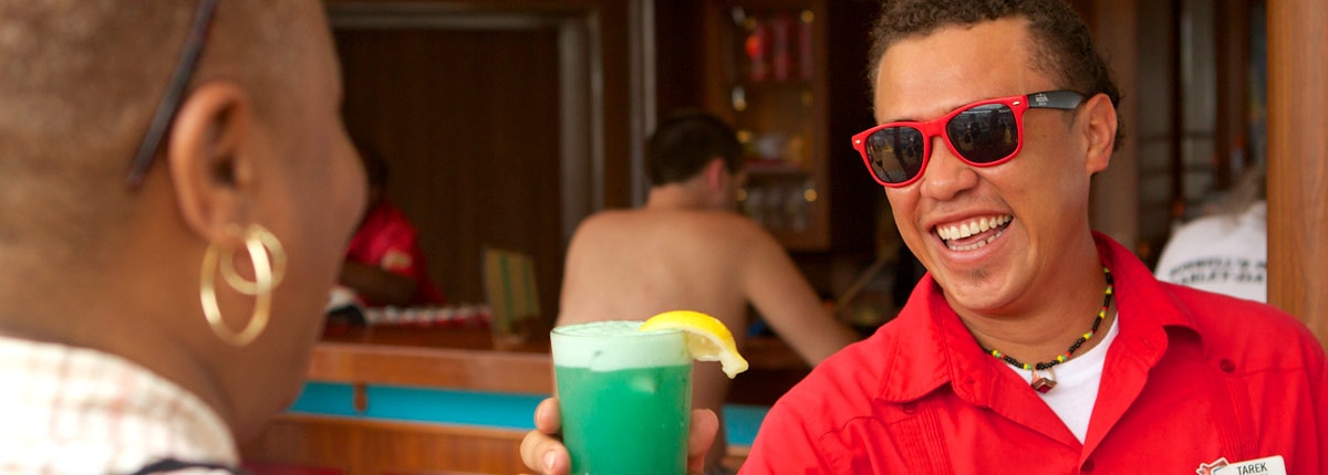 carnival crew member serving drinks at the red frog rum bar