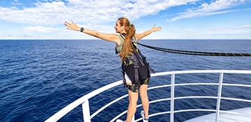guest standing on a railing wearing a safety harness