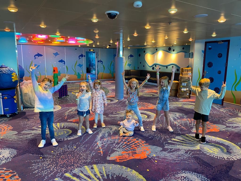 Group of children playing and posing in a colorful kids' area on a cruise ship.