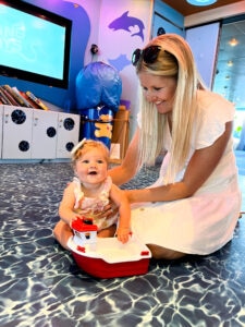 A mother playing with her baby with a toy boat.